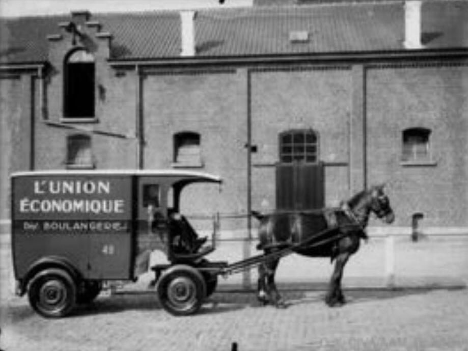 Photo d'archive : une voiture de livraison de l'Union Économique tirée par un cheval devant les bâtiments de la rue Artan