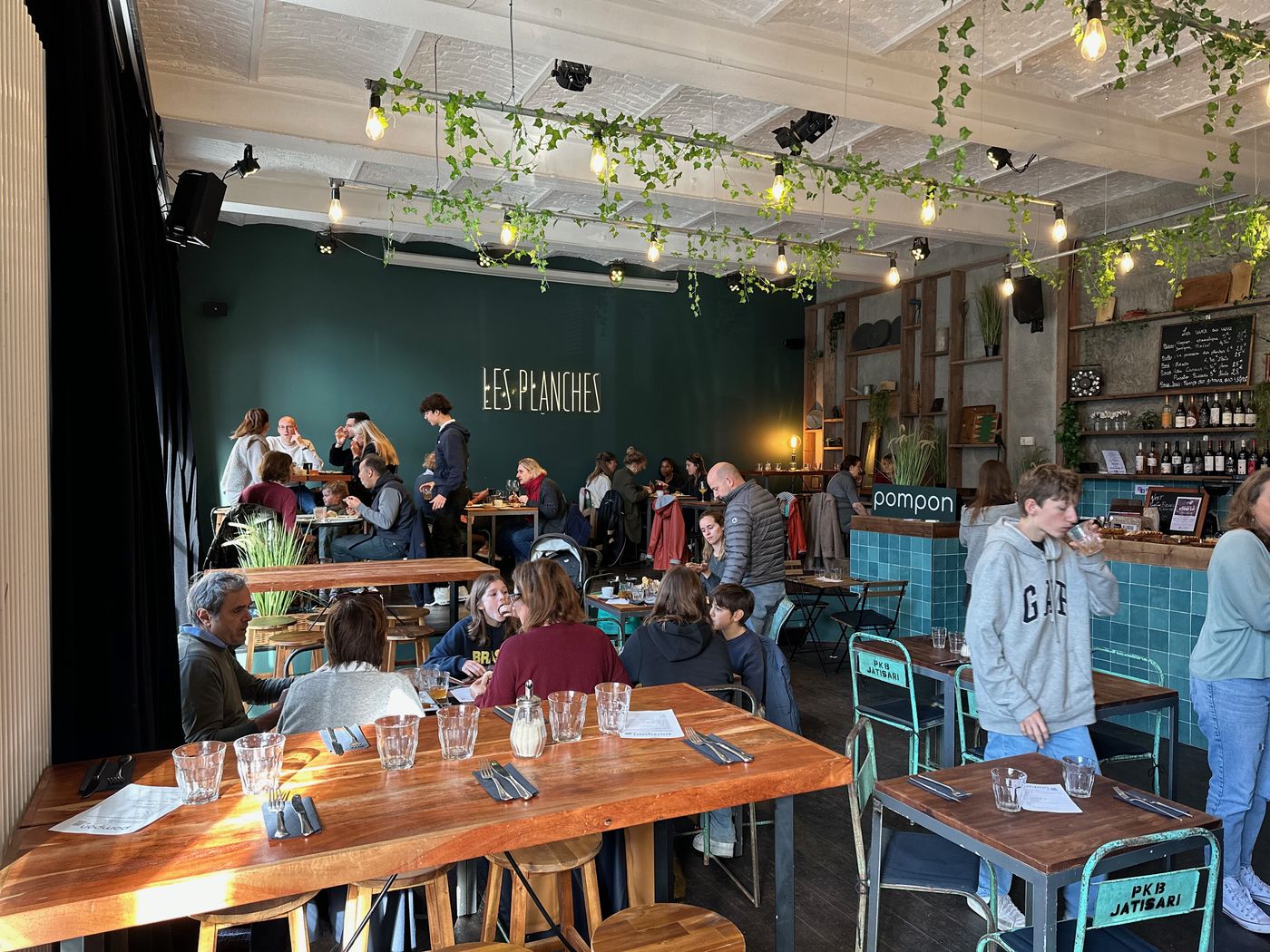 La salle en journée, tables en bois et bar carrelé
