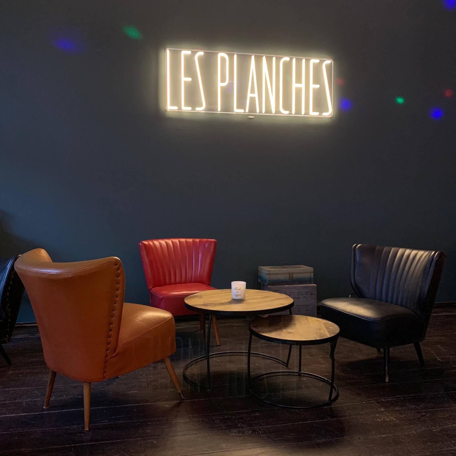Fauteuils en cuir rouge, orange et noir autour de tables basses en bois