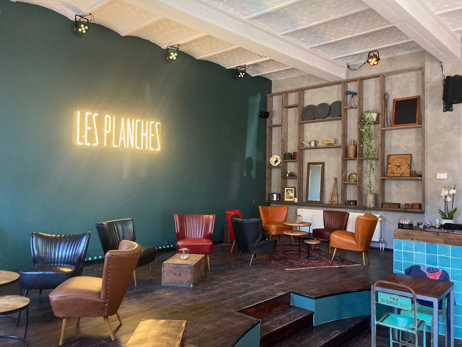 La scène avec le mur vert, le néon et les fauteuils en cuir